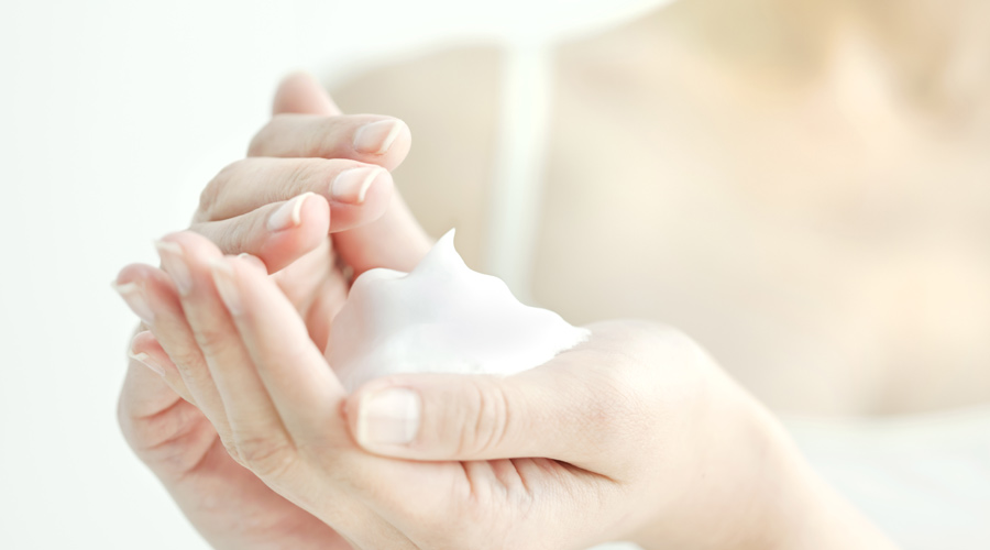 Plano detalhes que mostra duas mãos segurando uma espuma branca, simbolizando produtos para a pele com textura mousse.